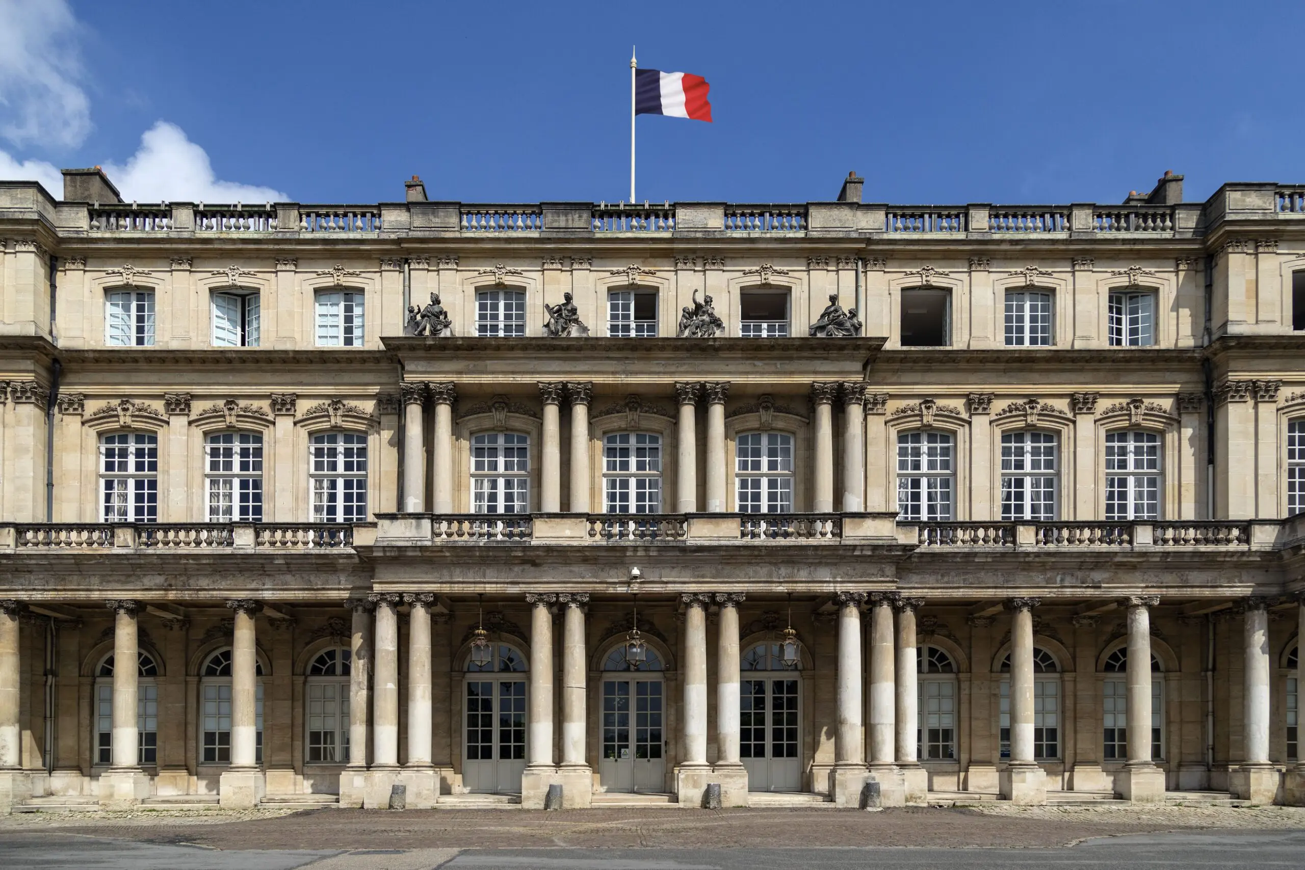 French government building flying the tricolor flag, representing the administrative center for residence permit renewals