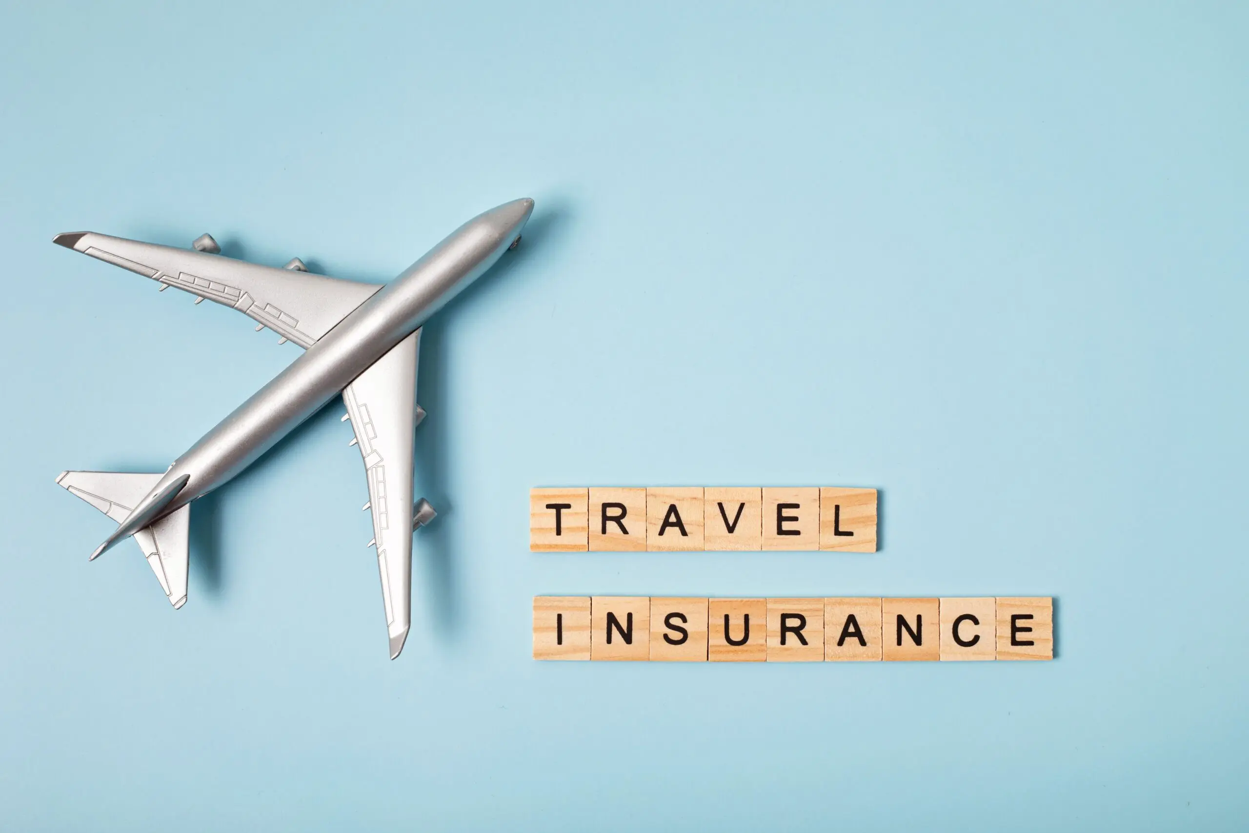 Toy airplane on a blue background with 'Travel Insurance' text, illustrating mandatory coverage for French long-stay visa applications