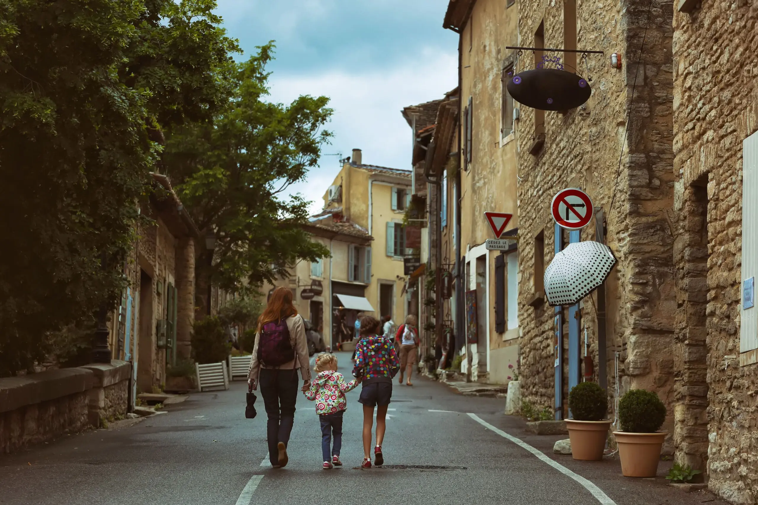 Mother and two children walking through a charming Provençal village street, illustrating the best places to live in France
