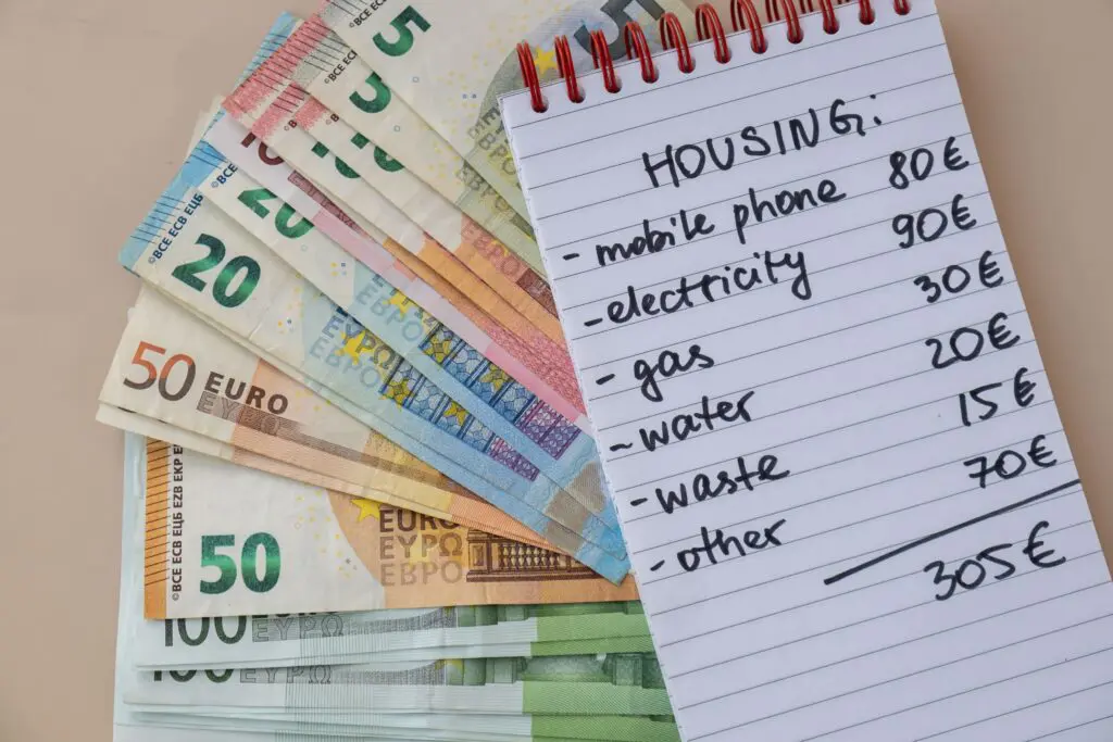Stack of euro banknotes beside a handwritten housing budget, illustrating the cost of living in France