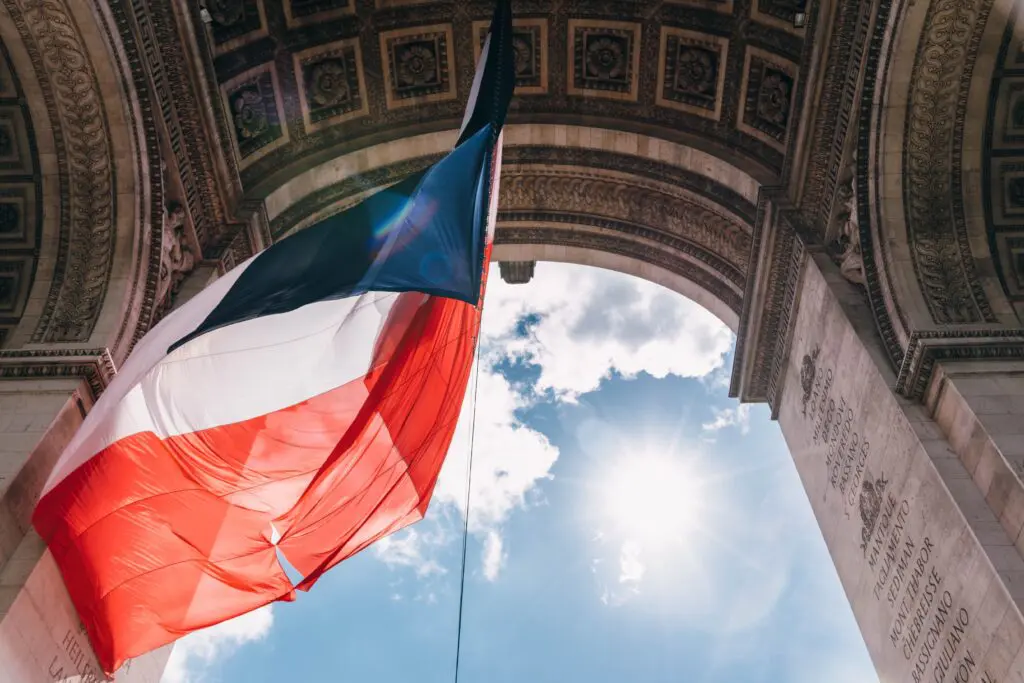 French flag flying under the Arc de Triomphe in Paris, symbolizing French citizenship reintegration