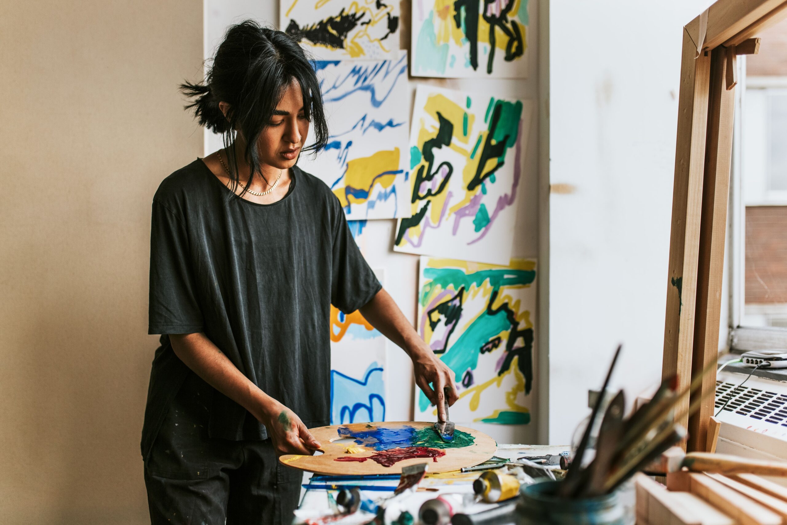 A painter mixing colours on a palette in her studio, representing an artist talent passport application in France